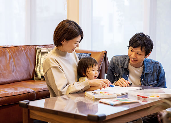 リビングのテーブルで子供とお絵描きを楽しむ夫婦