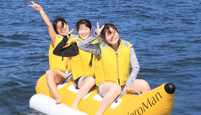 見る・遊ぶ情報の一覧ページへ 海上でバナナボートを楽しむ笑顔の女性3人組