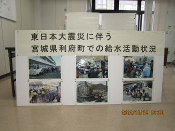 「東日本大震災に伴う宮城県利府町での給水活動状況」の文字の下に6枚の給水活動の様子の写真が展示されている写真